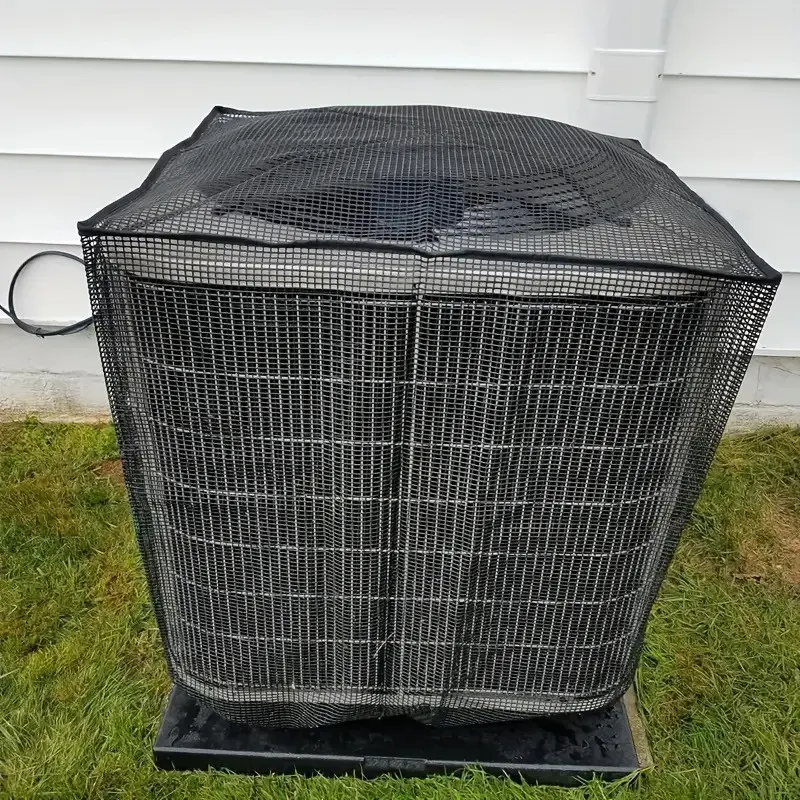 Black mesh protector installed over an outdoor air conditioner beside a house