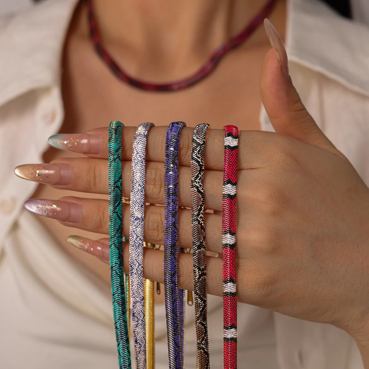 Hand holding the necklace in five different colourways