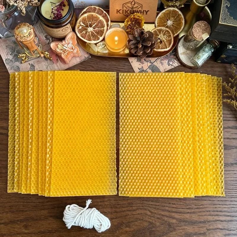 Golden beeswax candle making sheets and cotton wick laid out on a table