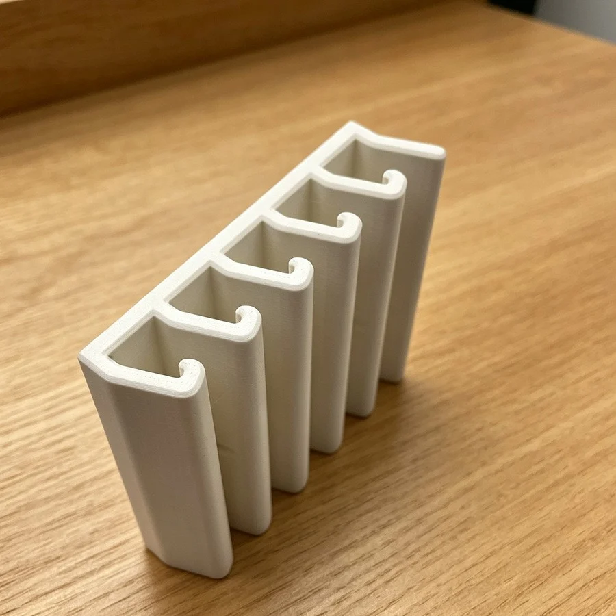 White five-slot food container lid organizer shown on a wooden surface from an angled close-up view