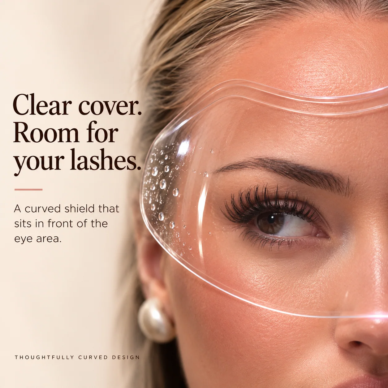 Close-up of an eye and eyelash extensions visible through the transparent curved shield